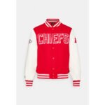 Model wearing red and gold Kansas City varsity jacket with chenille "KC" chest patch and Chiefs-inspired design